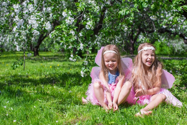 Petites filles avec des ailes de papillon dans le verger fleuri