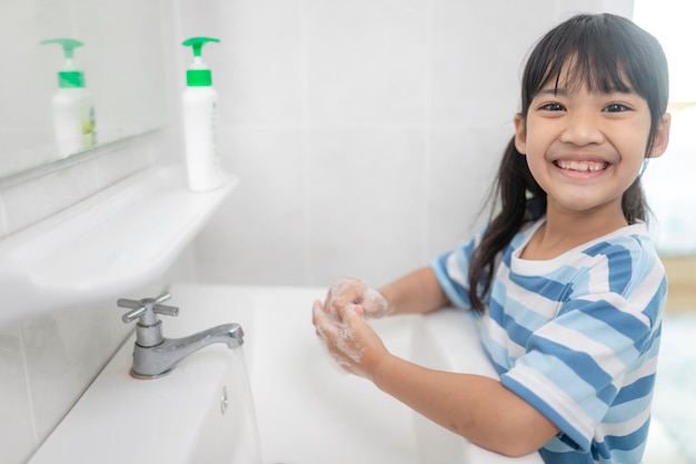 Les petites filles asiatiques se lavent les mains dans la salle de bain. Mise au point douce. Copiez l'espace.