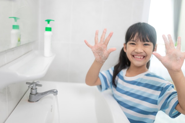 Les petites filles asiatiques se lavent les mains dans la salle de bain. Mise au point douce. Copiez l'espace.