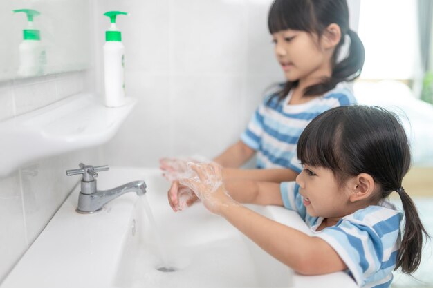 Les petites filles asiatiques se lavent les mains dans la salle de bain. Mise au point douce. Copiez l'espace.