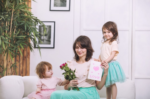 Les petites filles belles et mignonnes donnent des fleurs et des cartes mères dans la maison pour les vacances