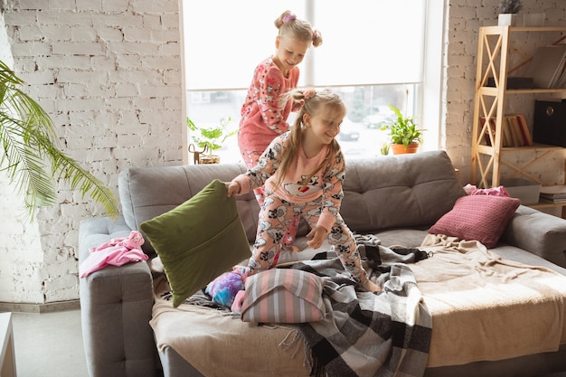 Petites filles calmes jouant dans une chambre en pyjama mignon style maison et confort