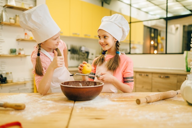 Les petites filles cuisinent dans des casquettes reniflant la poudre de vanille