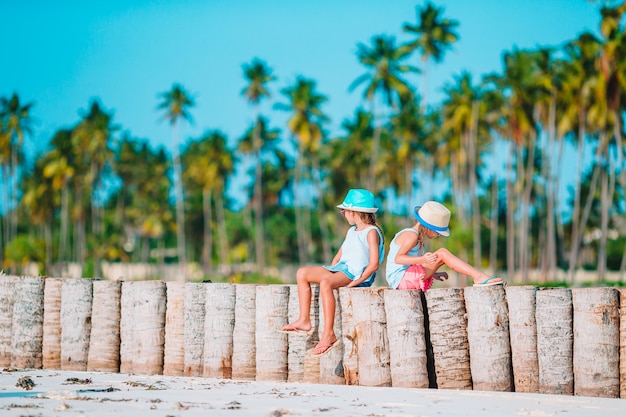 Les petites filles drôles heureuses s'amusent beaucoup sur la plage tropicale en jouant ensemble.