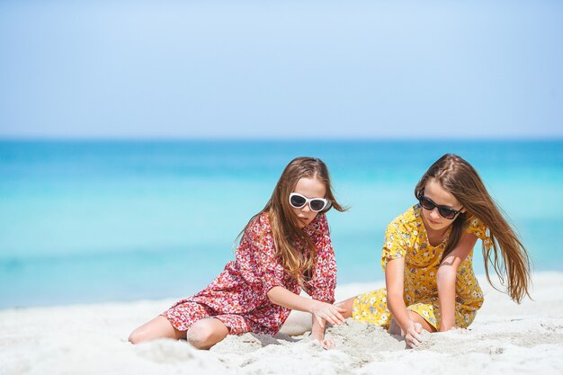 Petites filles drôles et heureuses s'amusent beaucoup à la plage tropicale en jouant ensemble