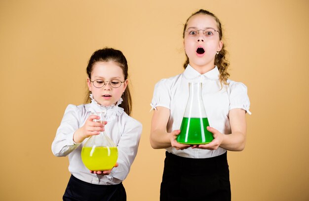 Les petites filles intelligentes avec des enfants en flacon de test étudient à la leçon de biologie la recherche scientifique dans les connaissances de laboratoire et l'éducation retour à l'école testant le liquide les enfants tiennent des bouteilles de test oh non