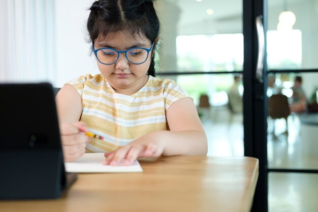 Petites filles mignonnes et heureuses utilisant un ordinateur portable, étudiant via un système d'apprentissage en ligne.