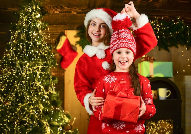 Petites filles préparant un cadeau de vacances. Recevoir des cadeaux. Fraternité et famille. Cadeau de Noël pour soeur. Les petites filles gaies tiennent une boîte-cadeau. Le lendemain de Noël. Enfants choisissant des cadeaux pour la famille.