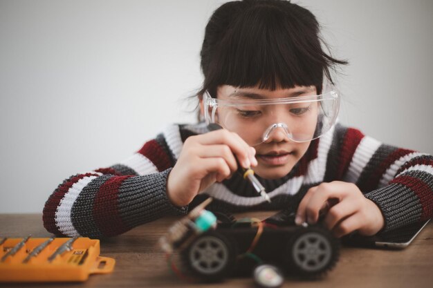 Petites filles s'amusant dans une voiture robot de codage d'atelier