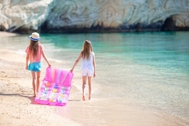 Petites filles s'amusant sur une plage tropicale jouant ensemble en eau peu profonde