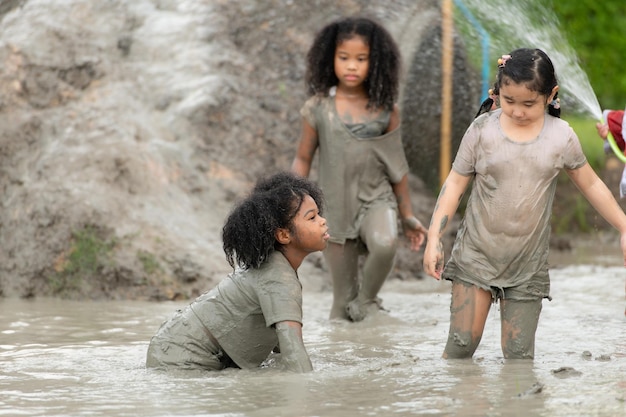 Les petites filles s'amusent à jouer dans la boue dans les champs communautaires.