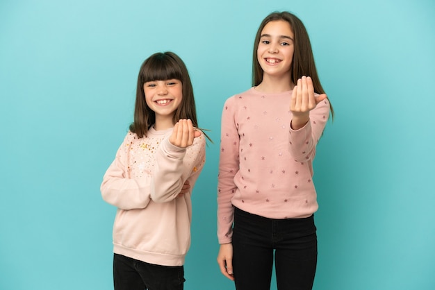 Petites filles sœurs isolées sur fond bleu invitant à venir avec la main. Heureux que tu sois venu