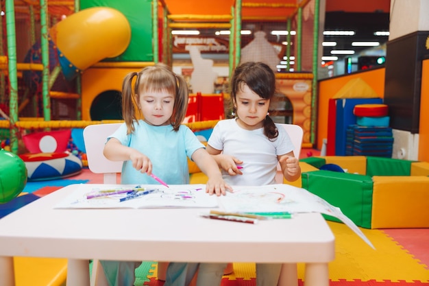 Les petites filles sont assises à une table et dessinent dans un centre de jeux pour enfants la créativité des enfants