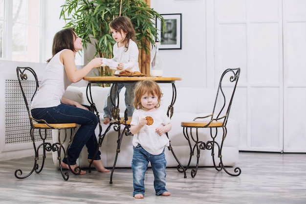 les petites filles sont belles et mignonnes avec leur mère à la maison en train de manger des biscuits