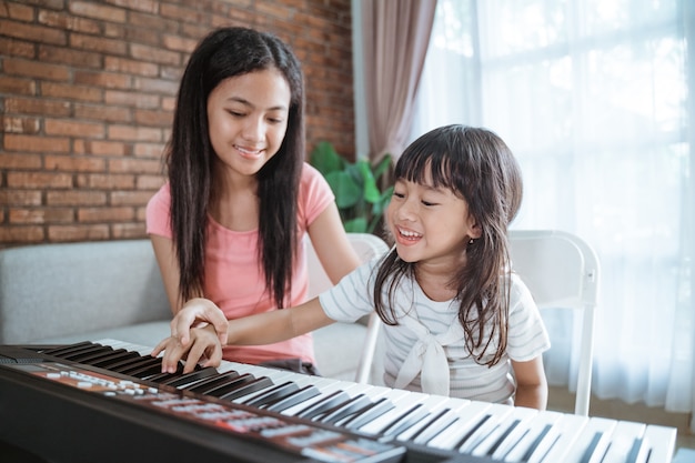 Les petites filles avec le sourire jouent un clavier d'instrument de musique