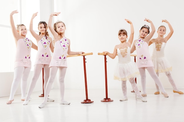 Petites filles utilisant la barre tout en pratiquant dans un studio de danse. Regarder la caméra.