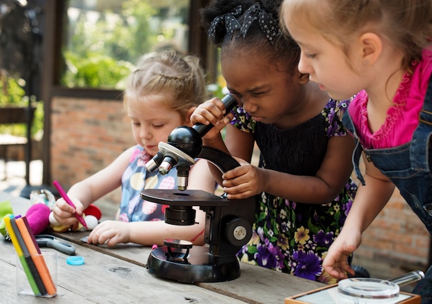 Petites filles utilisant la classe de science d&#39;apprentissage au microscope