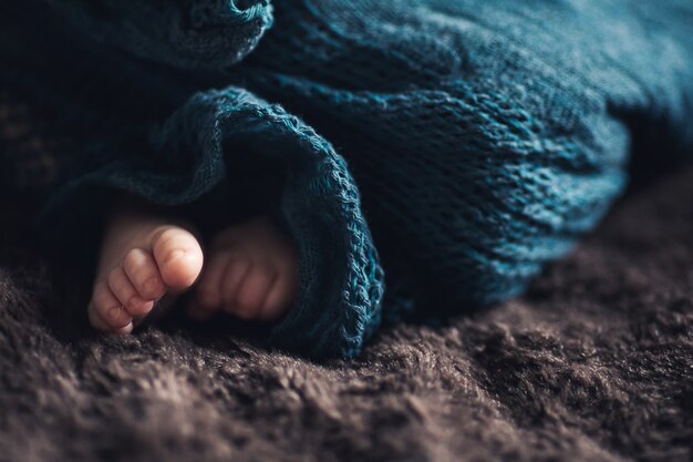 Les petites jambes du nouveau-né regardent sous une couverture.