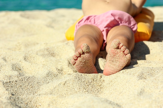 Petites jambes d'un enfant sur le sable sur la plage