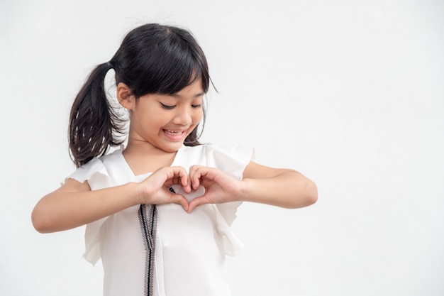 Petites mains de fille faisant une forme de coeur sur le fond blanc