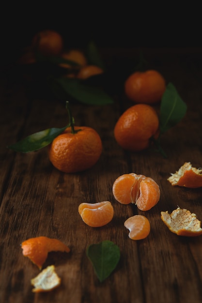 Petites mandarines avec des brins sur une table en bois.