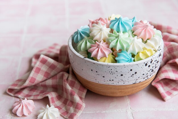 Petites meringues colorées dans le bol en céramique sur fond de carreaux