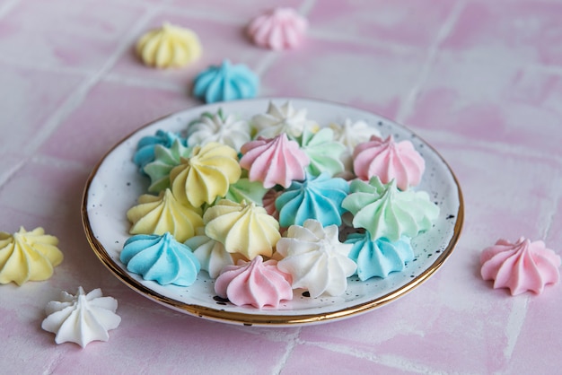 Petites meringues colorées dans la plaque en céramique sur fond de tuile rose