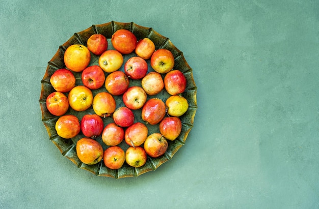 Petites pommes Ranetka rouges mûres sur une plaque de métal sur fond gris ou bleu