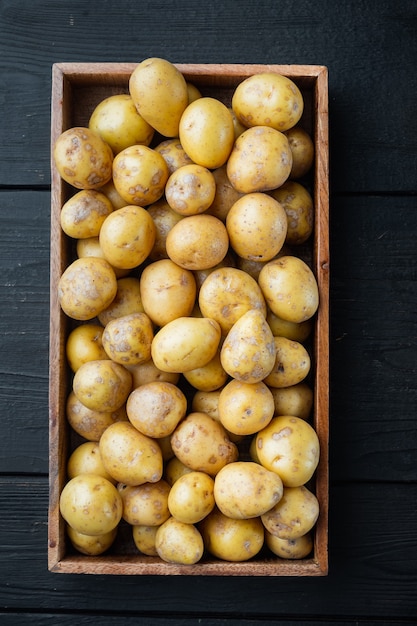 Petites pommes de terre rondes de pommes de terre rondes de l'Inde, dans une boîte en bois, sur une table en bois noir, vue de dessus à plat