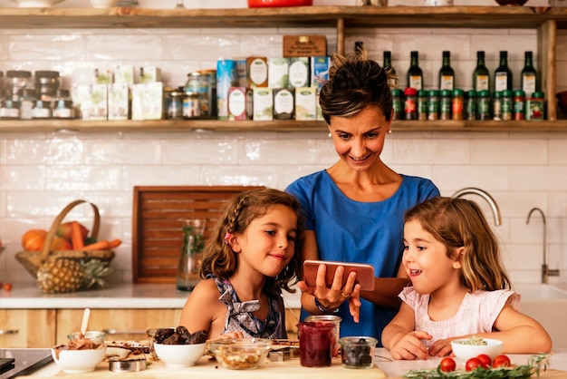 Petites soeurs cuisinant avec sa mère dans la cuisine. Concept de chef infantile.