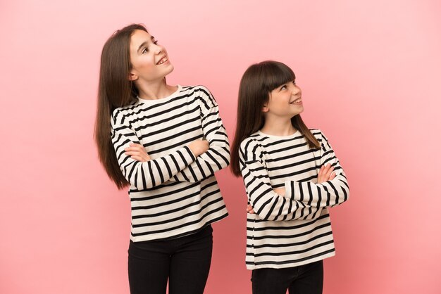 Petites sœurs filles isolées sur fond rose en levant en souriant