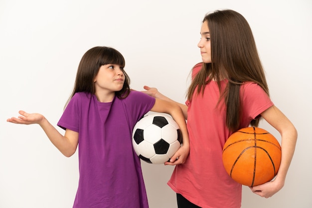 Petites soeurs jouant au football et au basket-ball isolées sur fond blanc faisant un geste sans importance tout en levant les épaules