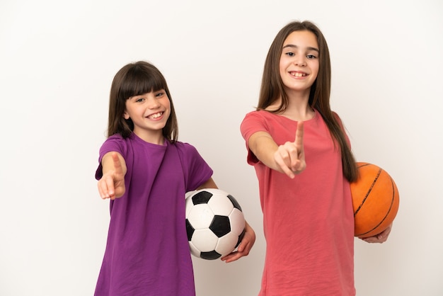 Petites soeurs jouant au football et au basket-ball isolées montrant et levant un doigt