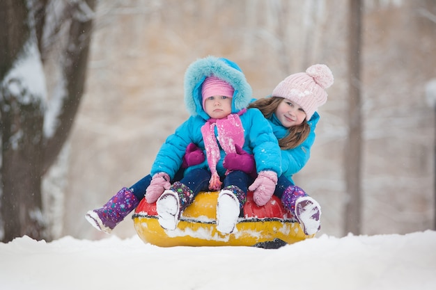 Petites sœurs montent dans un tube à neige à partir d'une heure d'hiver