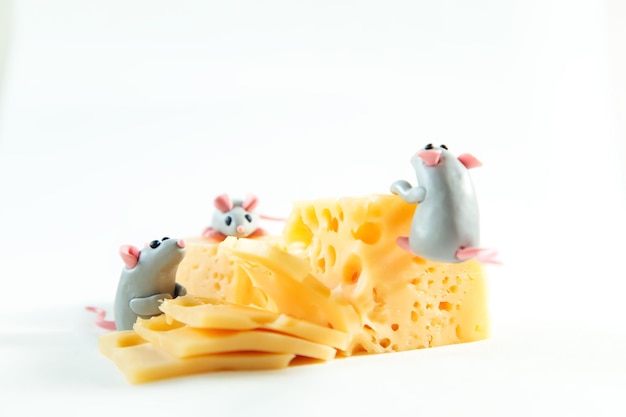 Des petites souris de plastique et un morceau de fromage avec des trous.