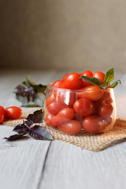 Petites tomates cerises se trouvent sur la table dans une tasse avec violet basel