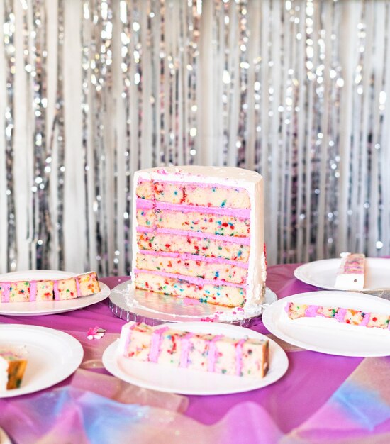 Petites tranches de gâteau d'anniversaire sur des assiettes en papier blanc.