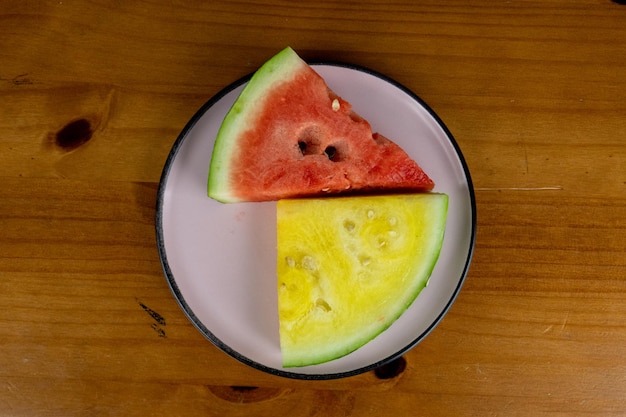 petites tranches de pastèque rouge et jaune servies sur une assiette blanche photographiée d'en haut