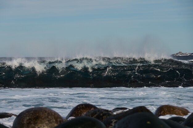 De petites vagues de la mer se brisent contre les pierres du rivage. Une belle journée ensoleillée et une mousse blanche des vagues.