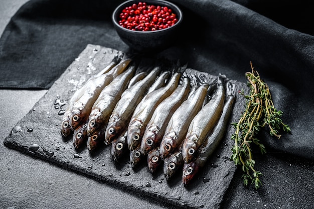 Petits anchois crus au poivre et au thym. Fond noir. Vue de dessus