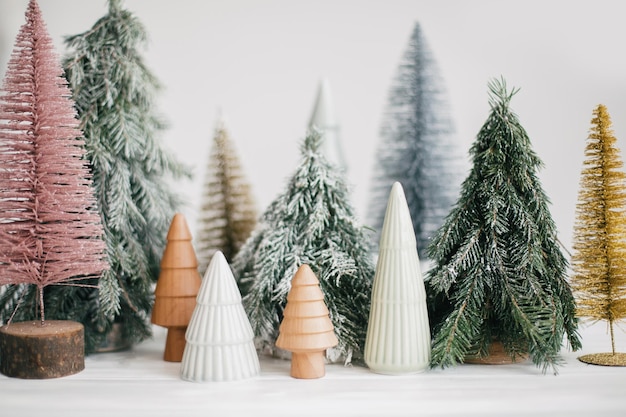 Petits arbres de Noël sur fond blanc Forêt d'hiver décor moderne festif Joyeuses fêtes Miniatures en céramique en bois enneigés et pins faits à la main Salutations de saison Joyeux Noël