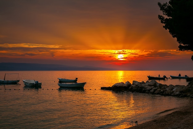 Petits bateaux avec un coucher de soleil sur la mer Adriatique sur un fond, Brela, Croatie