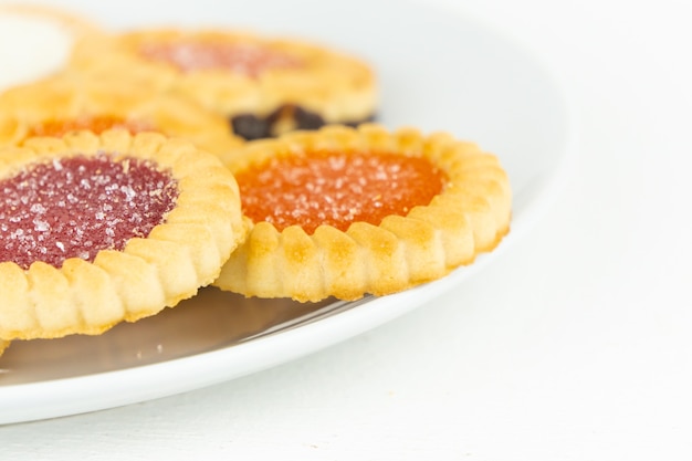 Petits biscuits tartelettes remplis de confiture de fruits sur une assiette blanche