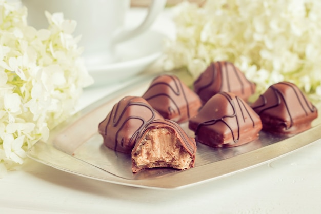 Les petits bonbons au chocolat se trouvent sur une assiette sur fond blanc