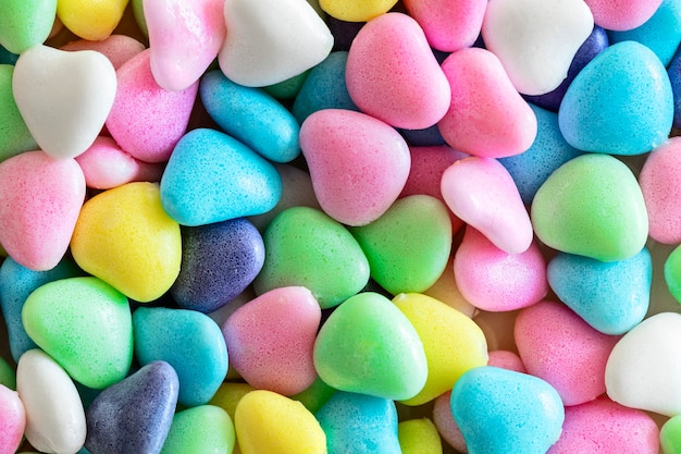 Petits bonbons colorés divers en forme de coeur, fond, gros plan