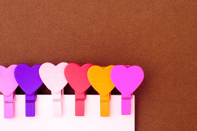 Les petits coeurs colorés tiennent une note en papier. Le concept d&#39;une note au jour de la Saint-Valentin