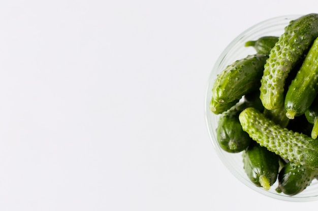 Petits concombres verts propres et frais dans un vase en cristal gros plan sur fond blanc
