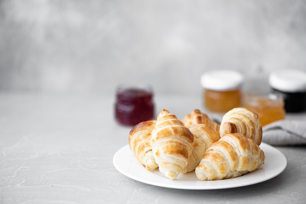 Petits croissants faits maison avec de la confiture sur une plaque blanche