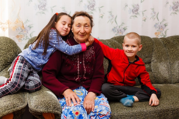 Des petits-enfants adultes souriants embrassent une grand-mère âgée heureuse de voir qu'elle lui manque, la visite de parents aimants apprécie la communication, les câlins comme symbole de connexion, d'amour et de concept de soutien