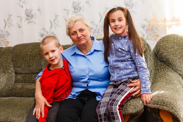 Des petits-enfants adultes souriants embrassent une grand-mère âgée heureuse de voir qu'elle lui manque, la visite de parents aimants apprécie la communication, les câlins comme symbole de connexion, d'amour et de concept de soutien